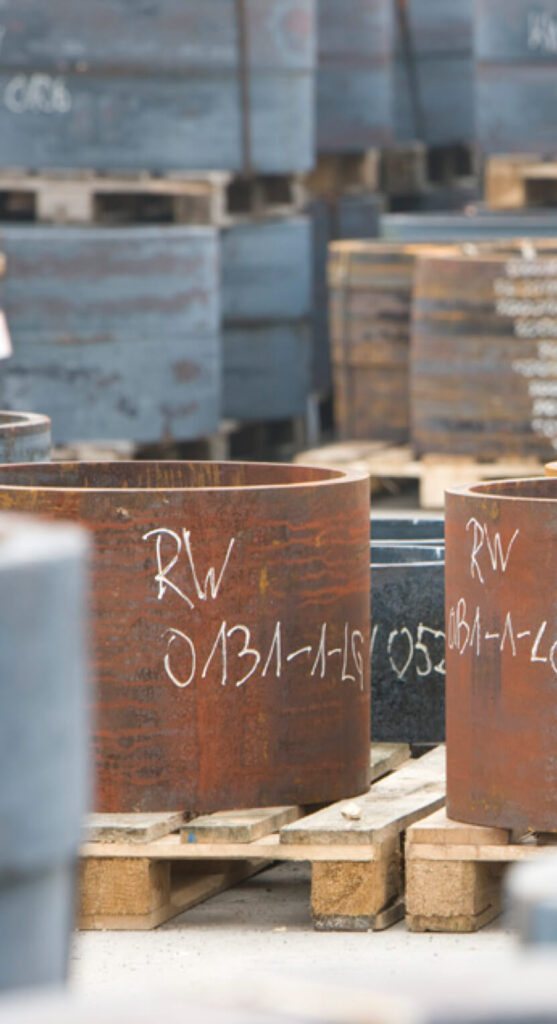 Außenlager mit Vormaterial für die CNC-Fertigung von Präzisionskomponenten – auf Europaletten gelagerte Rundstahlzuschnitte unterschiedlicher Güten und Durchmesser.